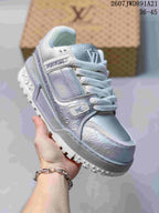 Angled side view of the silver and white sneaker showing the patterned upper, branding, and textured tread.