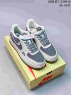 Pair of white and gray Nike Air Force 1 '07 Low sneakers displayed on a shoebox.
