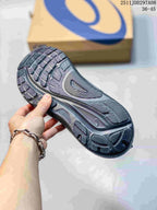Close-up of the dark gray sneaker outsole showing its layered tread pattern and ASICS shoe box in the background.