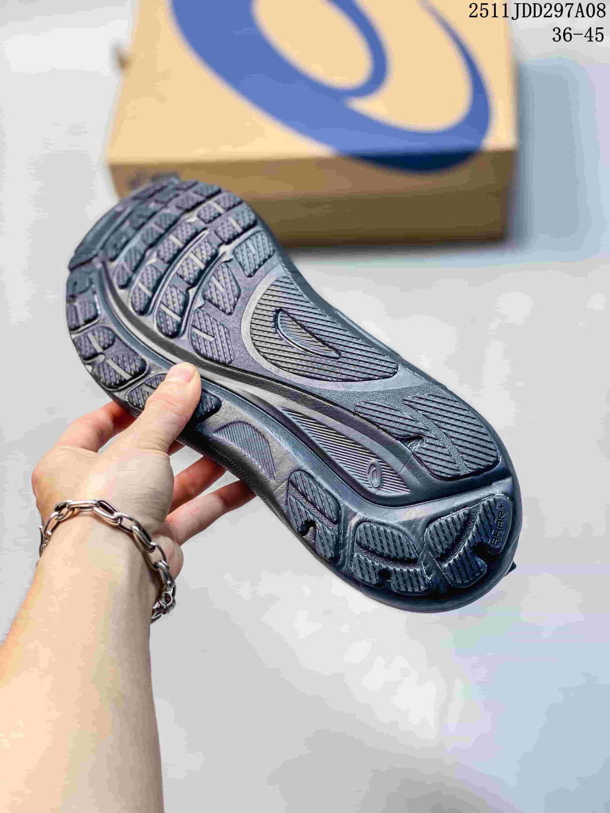 Close-up of the dark gray sneaker outsole showing its layered tread pattern and ASICS shoe box in the background.