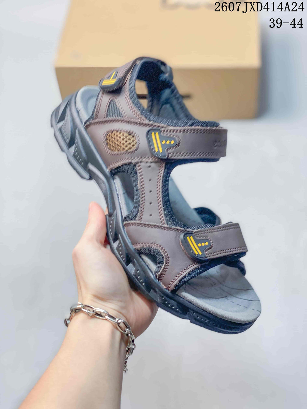 Angled side view of the brown open-toe sandal showing its adjustable straps, ventilated side panel, and dark outsole.