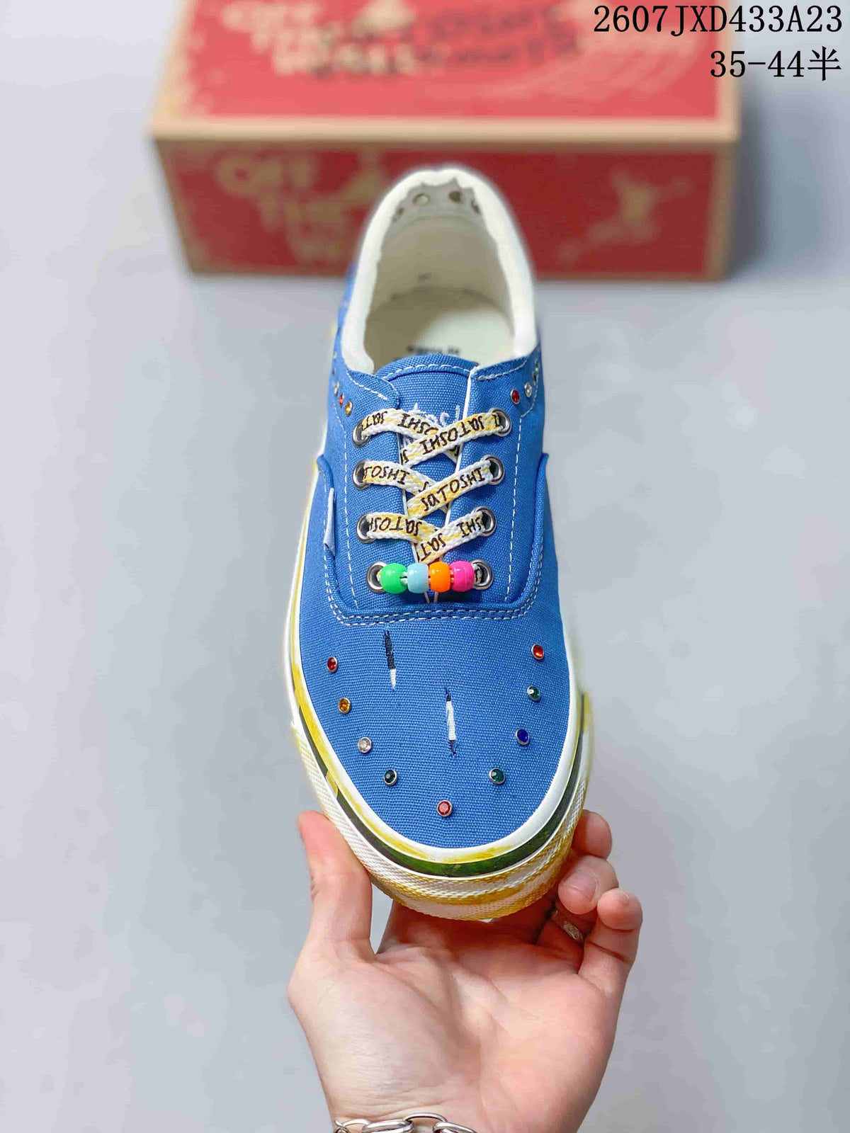 Top view of the blue sneaker showing the lace area, multicolor eyelets, beaded lace accent, and white stitching.