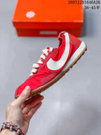 Side profile of the red low-top sneaker with a large white Swoosh, cream midsole, and gum outsole.