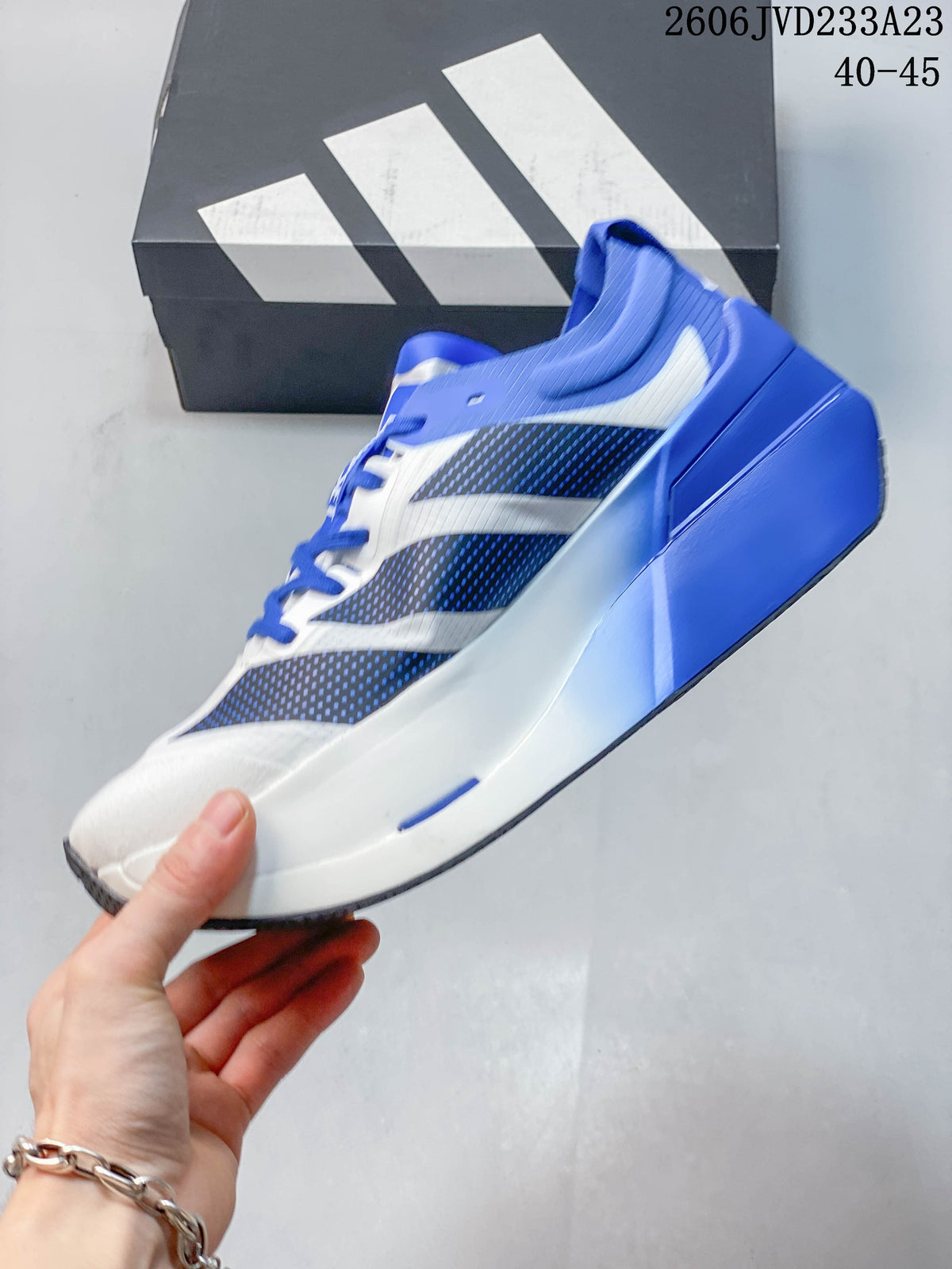 Side view of the white and blue running shoe with dark patterned panels and sculpted midsole; image overlay shows EU size range 40–45.