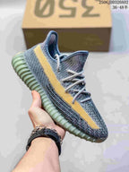 Gray knit sneaker with a yellow side stripe, light laces, and a pale green-gray ribbed sole.