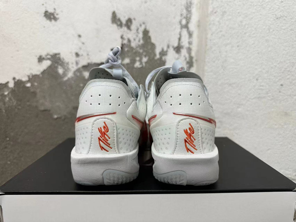 Rear view of white Nike sneakers with red accents and heel branding
