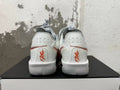 Rear view of white Nike sneakers with red accents and heel branding