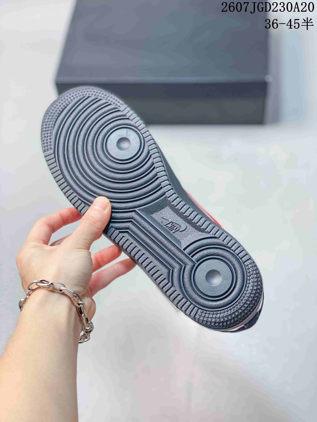 Close-up of the black rubber outsole showing concentric circular traction patterns and Air branding; a shoebox is visible in the background.