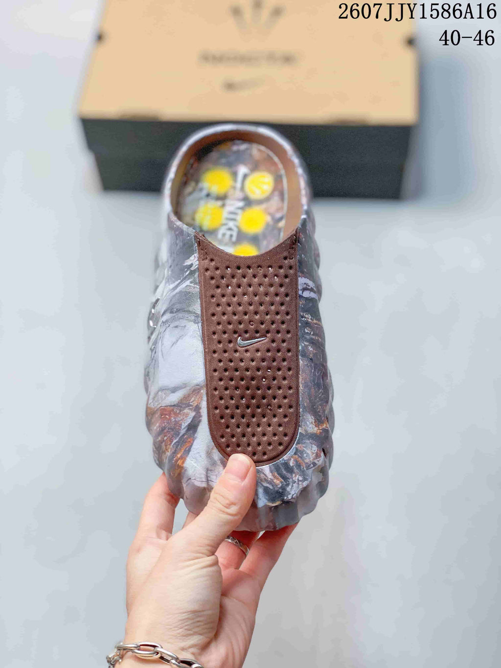 Top view of a single sandal showing the brown perforated strap, small logo detail, and marbled footbed area.