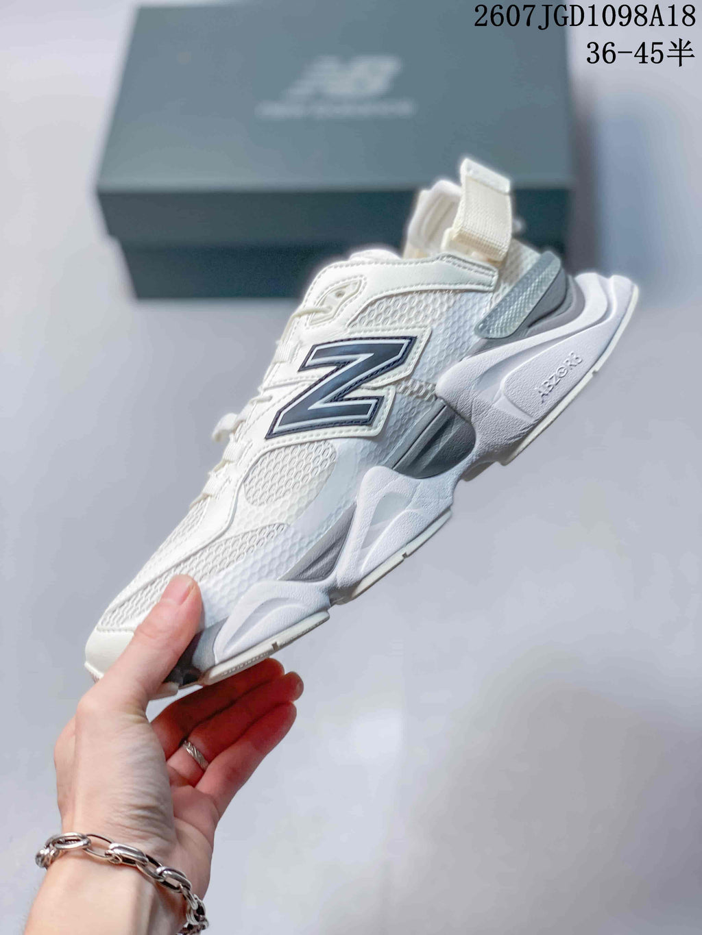 Side profile of a white and light grey New Balance 9060 sneaker highlighting the large contrast N logo, mesh panels and sculpted midsole.