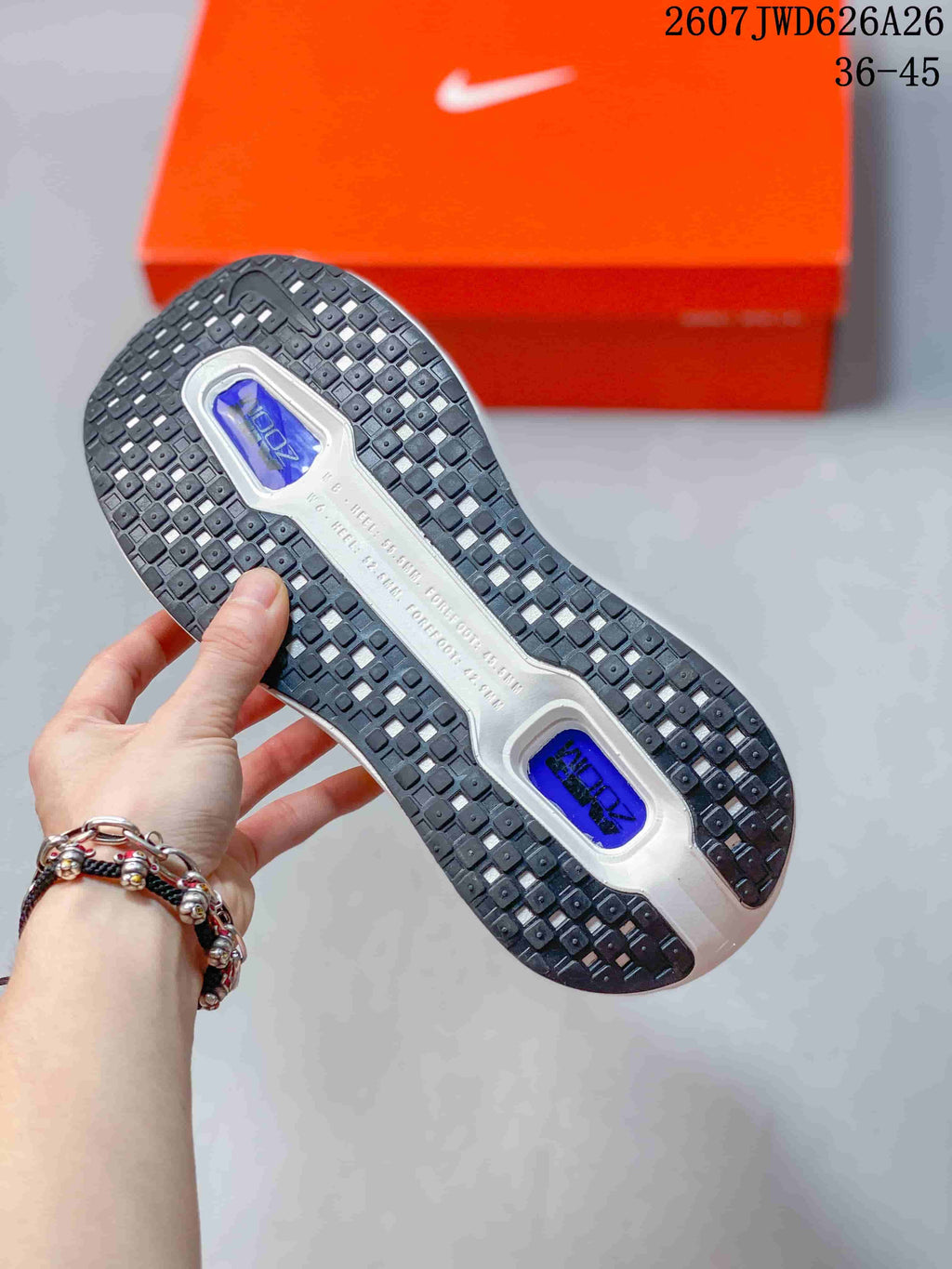 Bottom view of a sneaker showing the black patterned outsole and blue cushioning windows.