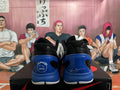 Rear view of black, white, and blue basketball sneakers displayed on a shoebox.