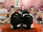 Rear view of black Nike basketball shoes with green accents, light speckled midsoles and an orange shoe box.