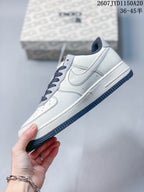 Side profile of the white low-top sneaker showing layered panels, a Swoosh-shaped side detail and dark navy outsole.