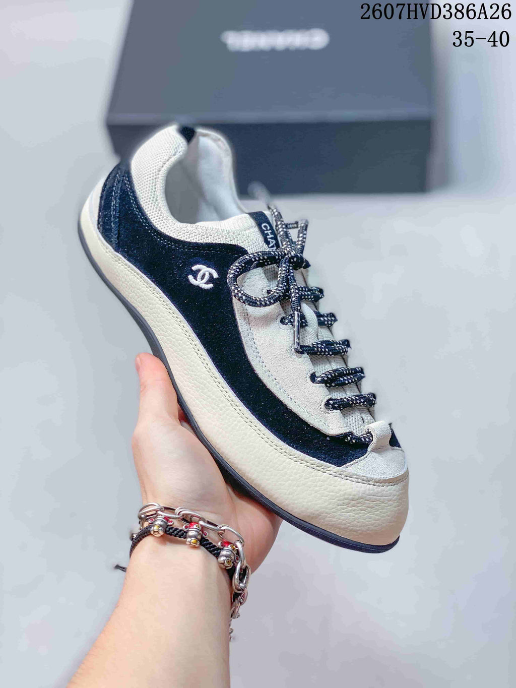 Angled side view of the sneaker showing the black side panel, white lower section, lace detail and visible Chanel branding.