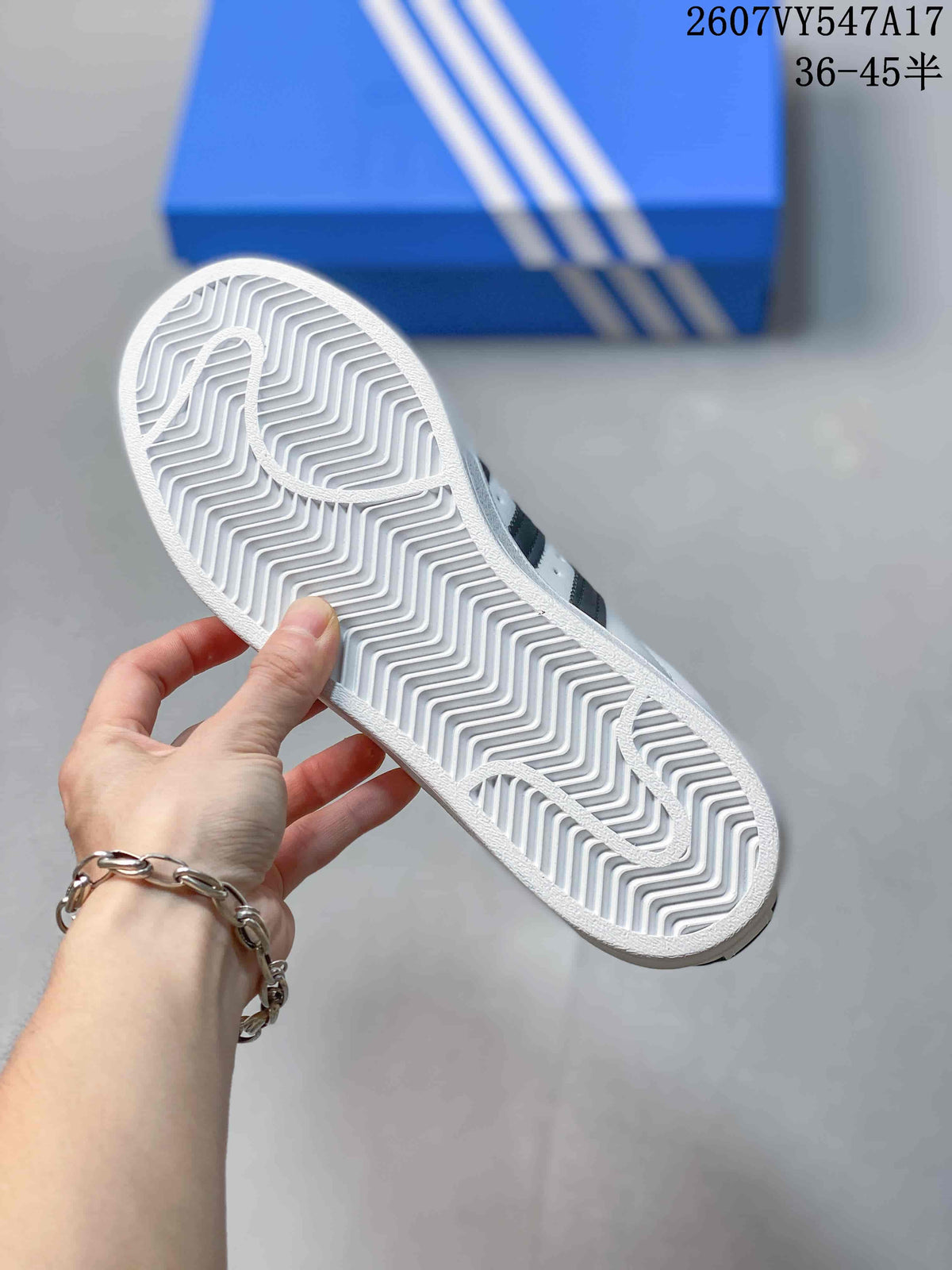 Underside of a white sneaker showing the patterned rubber outsole and zigzag tread.