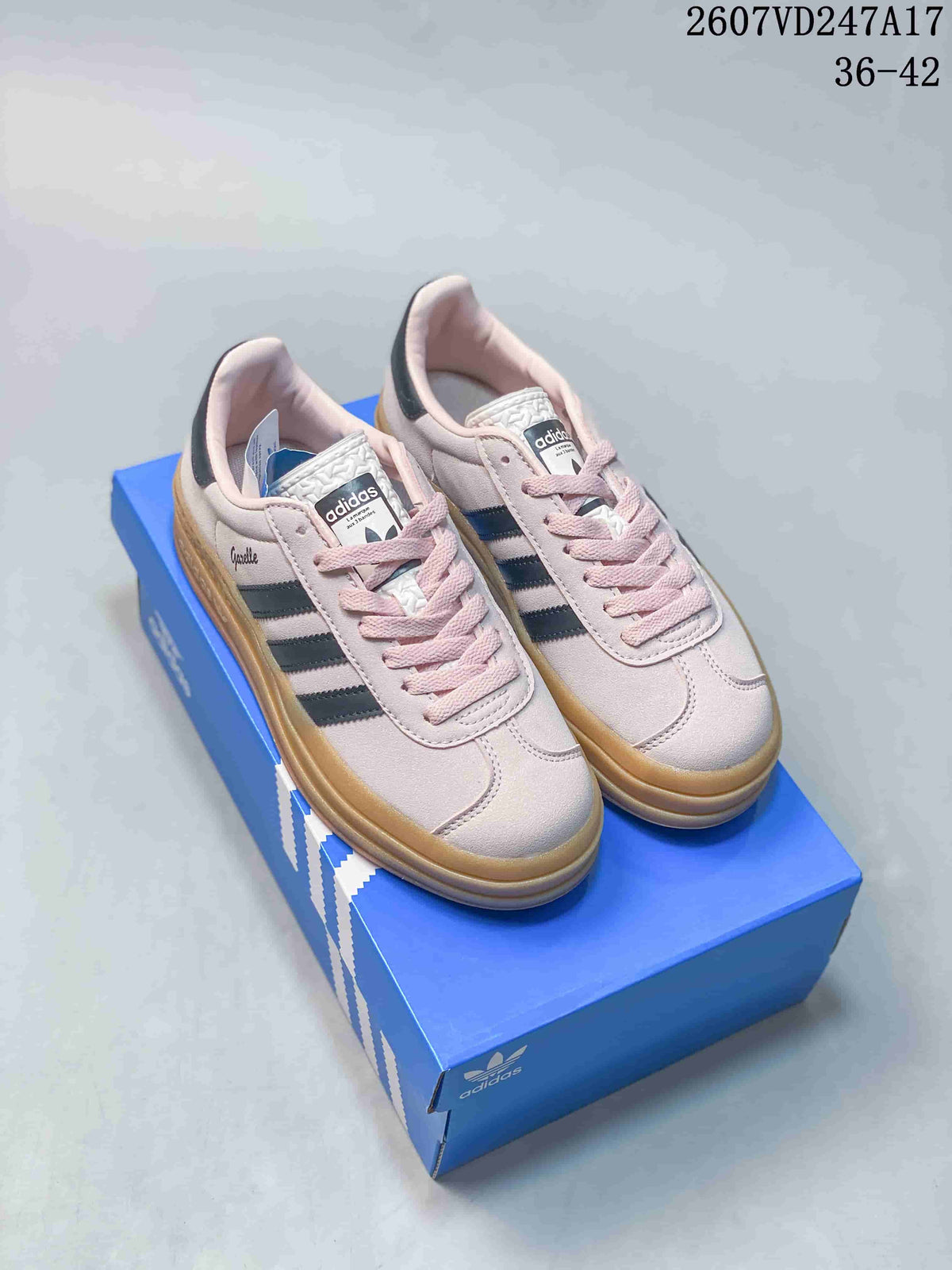 Pair of pale pink adidas Gazelle sneakers with black stripes and gum platform soles displayed on a blue shoebox.