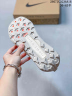 Close view of the white outsole showing a lugged traction pattern with geometric tread blocks and circular openings.