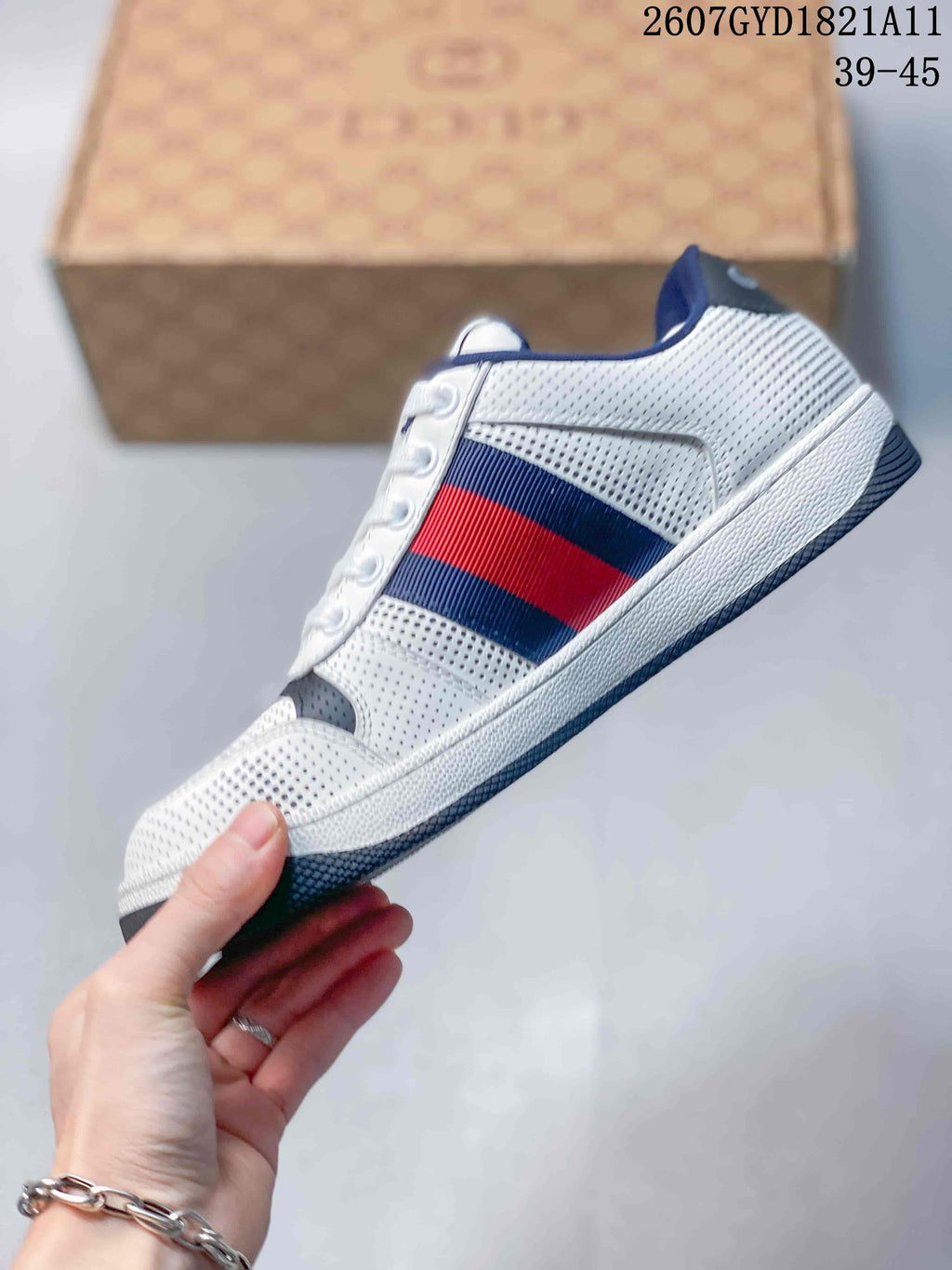 Side profile showing the perforated white upper, navy and red stripe panel, white midsole, and dark outsole.