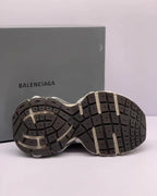 Bottom view showing the segmented patterned rubber outsole of the sneakers.