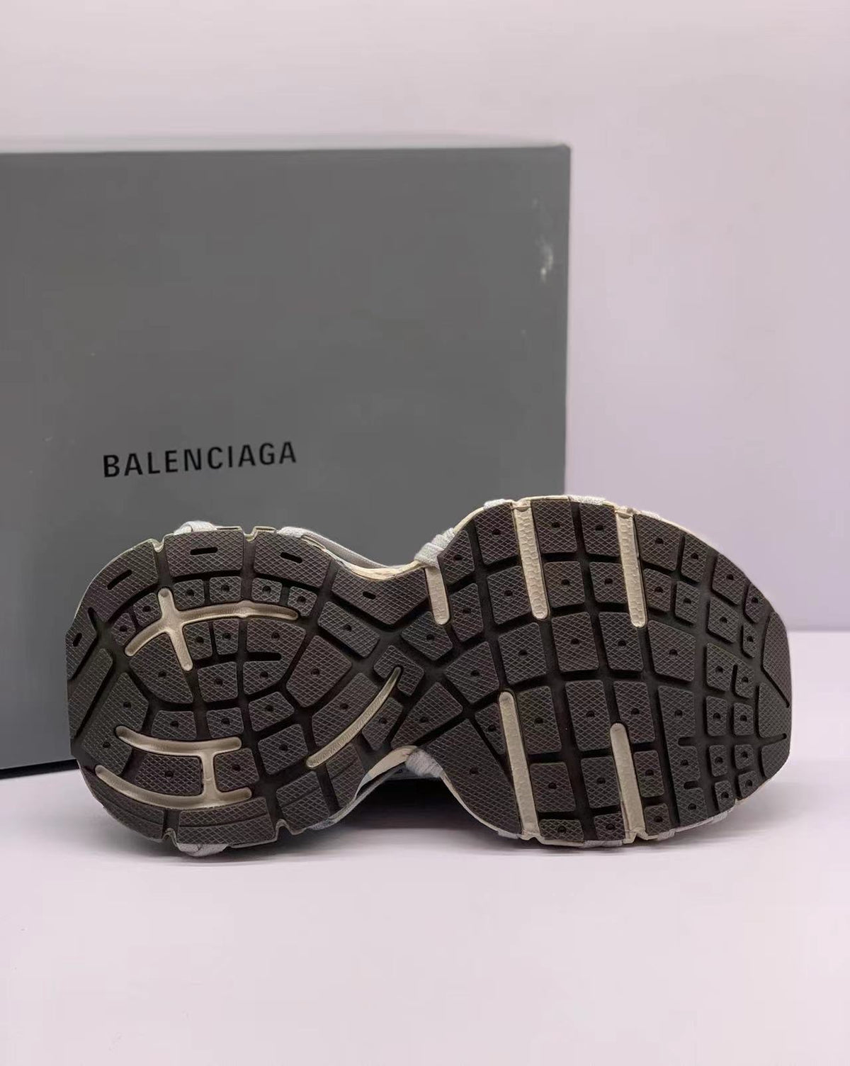 Bottom view showing the segmented patterned rubber outsole of the sneakers.