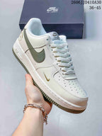 Side view of a white Nike Air Force 1 '07 Low sneaker with olive-colored accents
