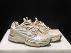 Three-quarter view highlighting the cream upper, white side arrows, beige accents, and sculpted midsole.