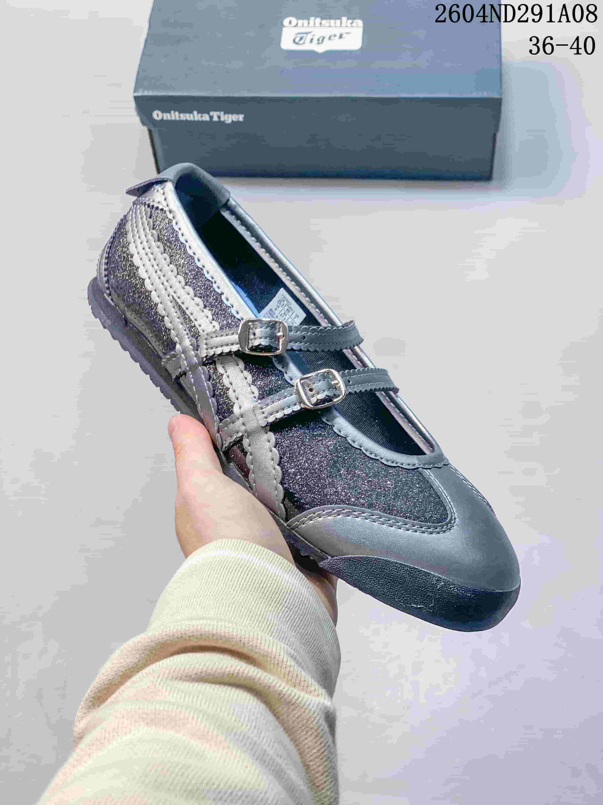 Angled side view showing the two buckle straps, side branding stripes, gray and silver upper, and textured outsole.