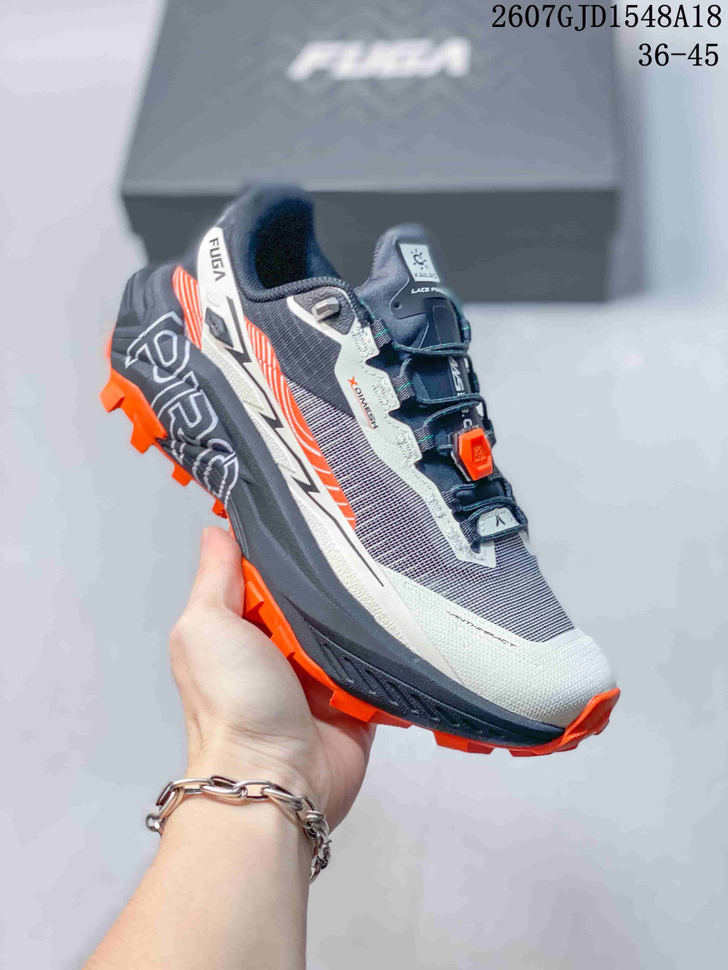 Angled side view showing the KAILAS FUGA shoe, gray and white upper, orange accents, and layered trail outsole.