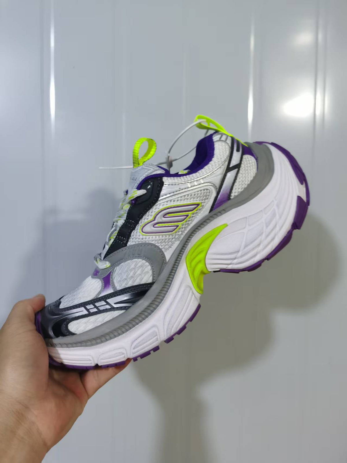 Close angled view of the Skechers 9157 sneaker showing layered side overlays, mesh-like panels, grey trim and purple outsole details.