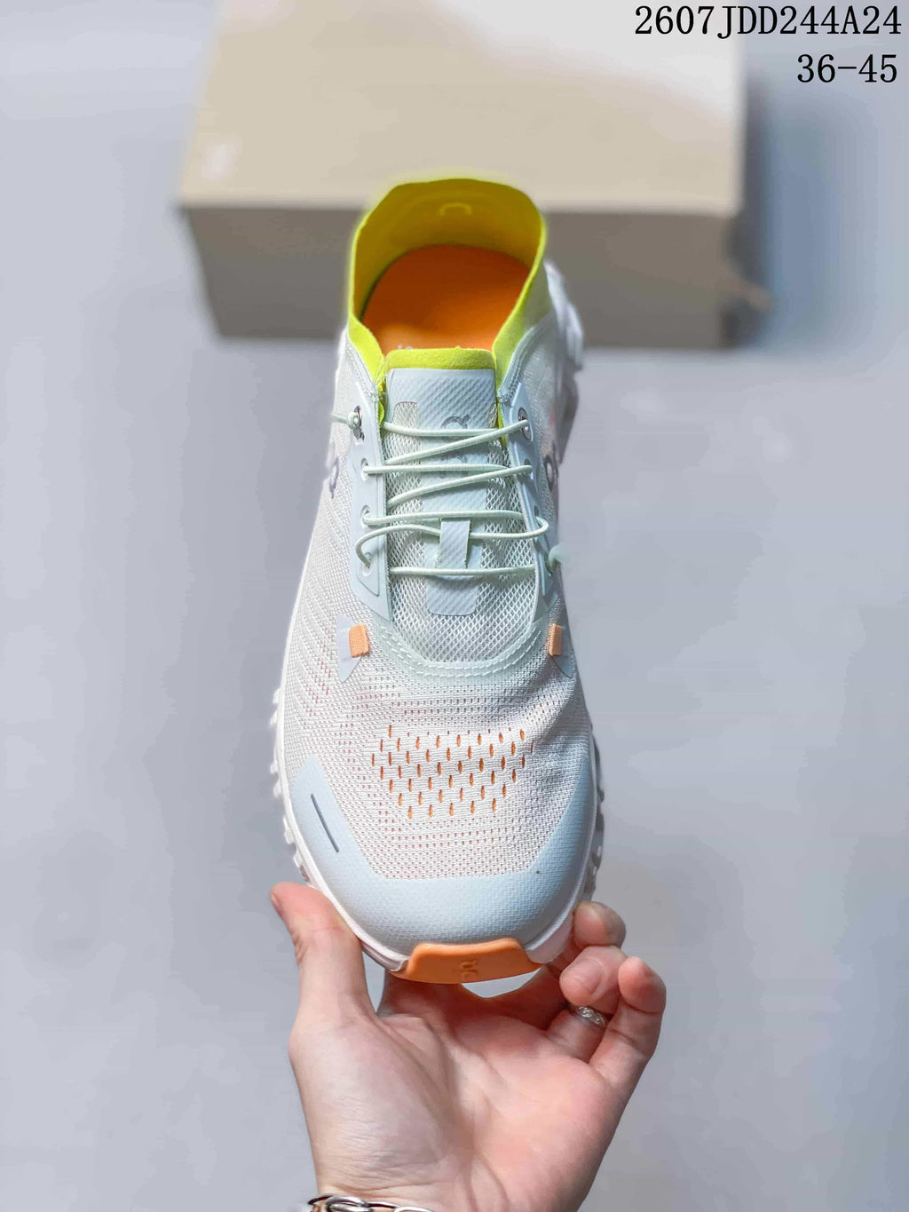 Top view of the sneaker showing the rounded toe, pale blue upper, white laces, neon yellow-green lining, and orange accents.