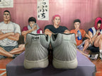 Rear view of light gray-white Nike basketball shoes with “12AM” heel tabs and dark speckled outsoles.