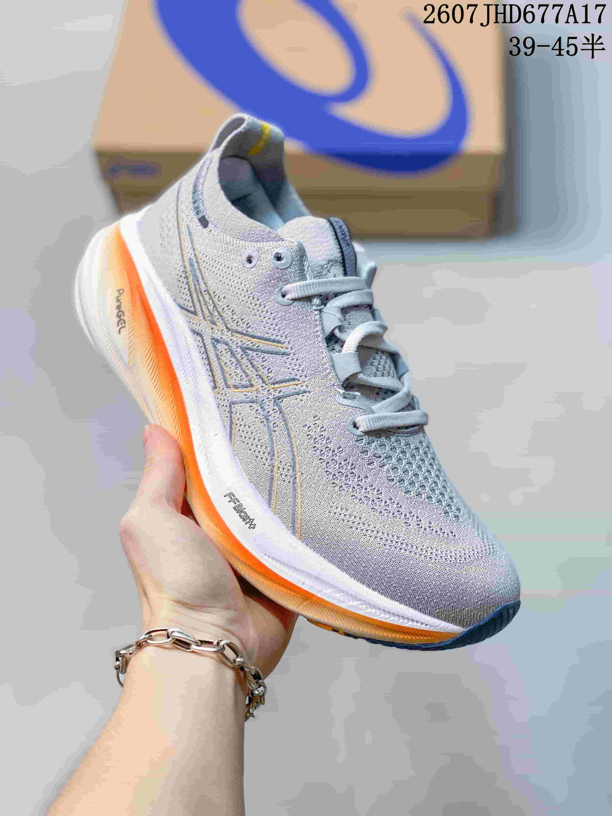 Angled side view of the gray ASICS GEL-NIMBUS 26 sneaker showing the textile upper, logo overlays, orange midsole accent, and dark outsole.