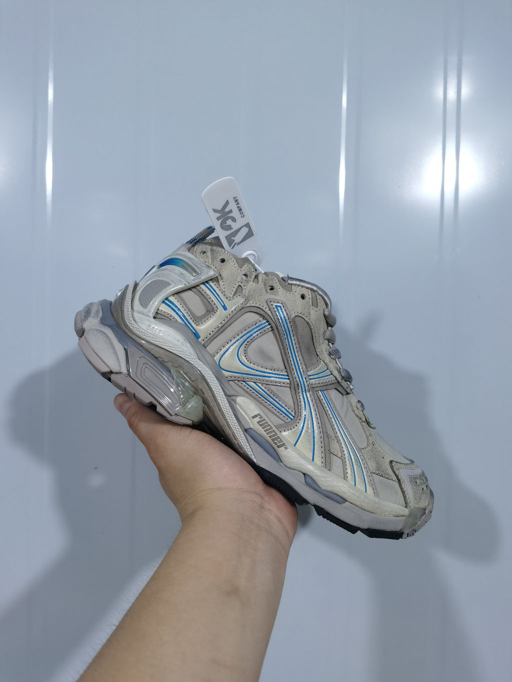 Close angled view of the taupe and blue Puma 2240 Runner sneaker showing layered side panels, mesh sections, blue accents, and sculpted sole details.