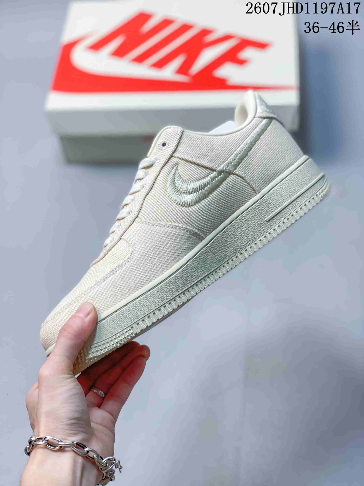Side profile of the cream low-top sneaker showing the woven upper, embroidered Swoosh, layered panels, and textured outsole.