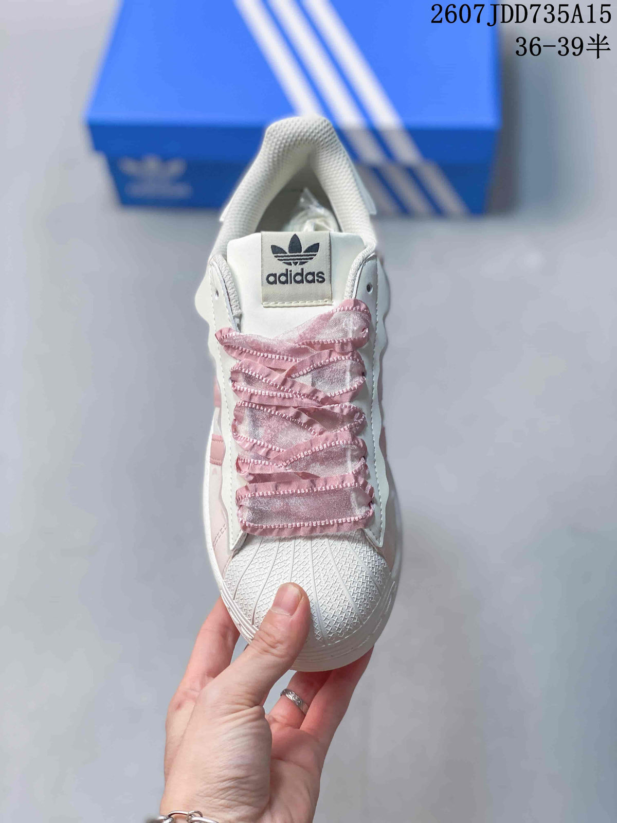Top view showing the trefoil tongue label, ruffled pink laces, and textured shell toe.