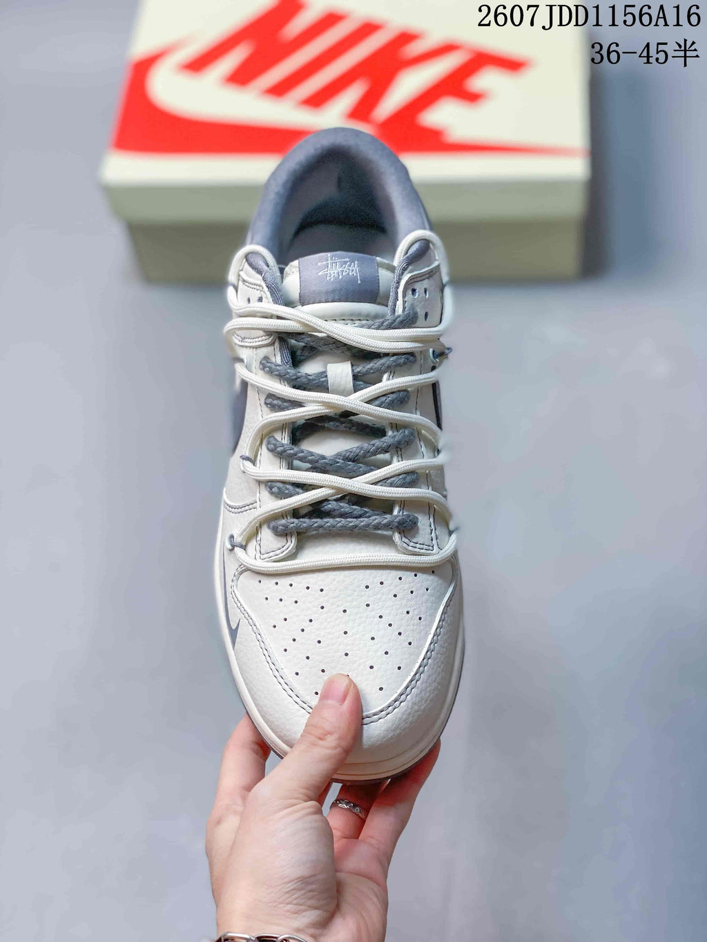 Top view of an off-white and gray low-top sneaker showing the perforated toe box and layered laces; image text shows style code 2607JDD1156A16 and size range 36–45.5.