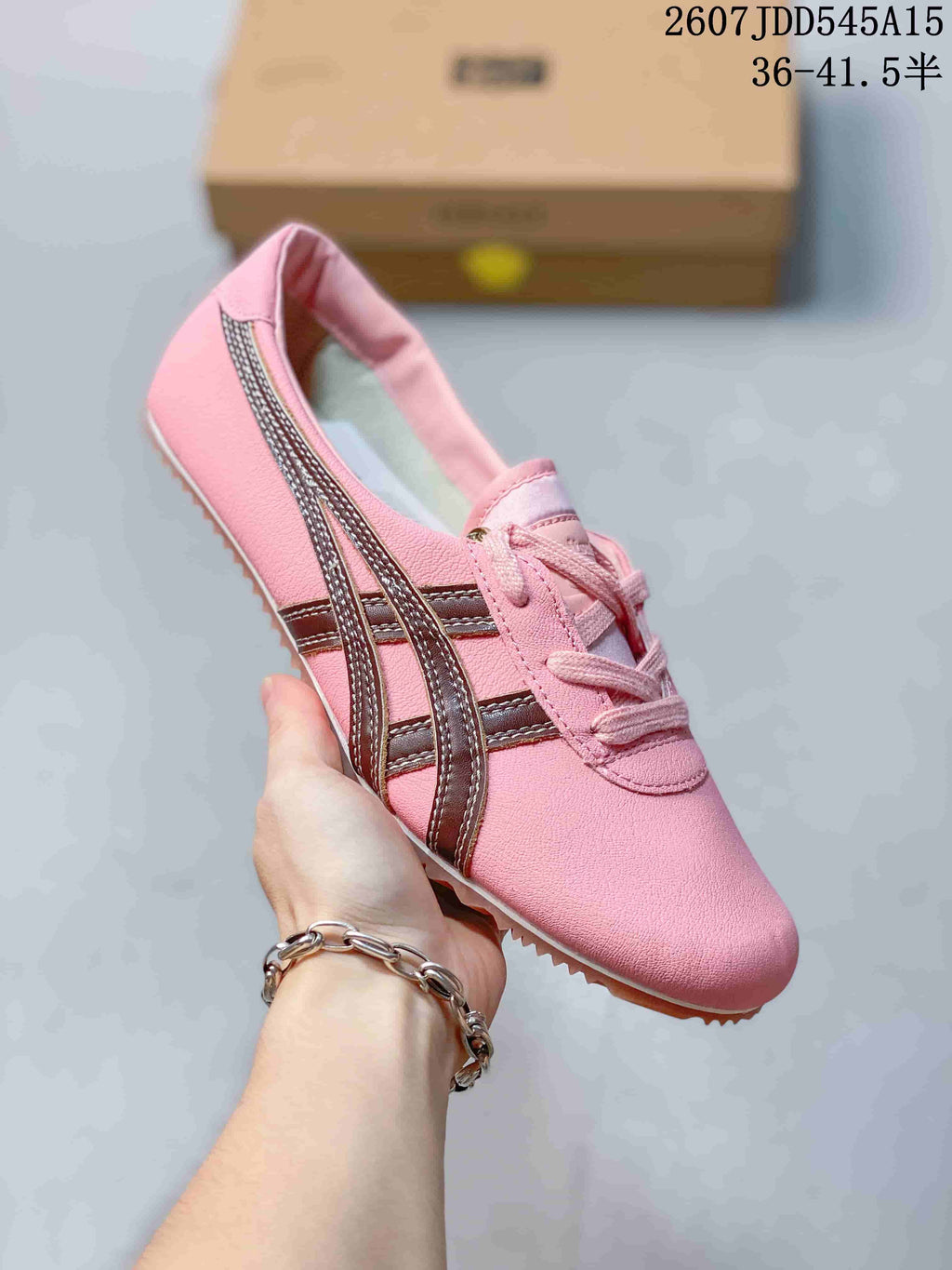 Pink low-top sneaker with brown side stripes and matching pink laces.