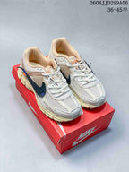 Pair of Nike Zoom Vomero 5 sneakers displayed on a red Nike shoebox, showing the white and cream upper with navy accents.