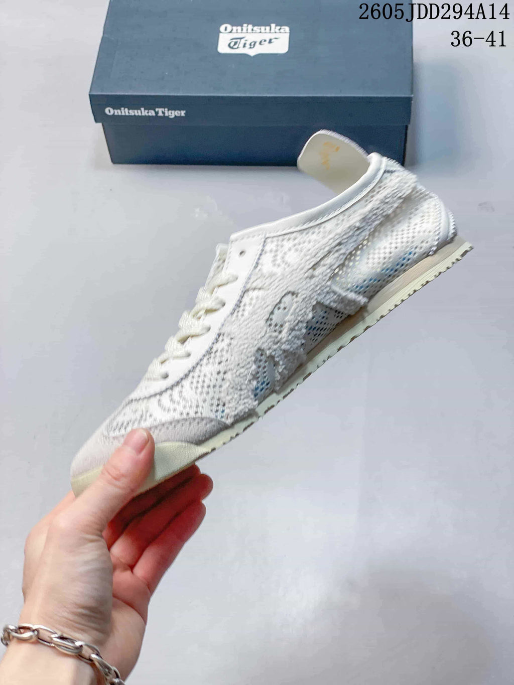 Side profile of the white and grey Onitsuka Tiger sneaker showing the mixed-panel textile upper and low-top shape.