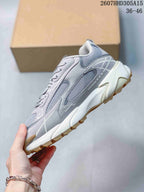 Side profile of the gray sneaker showing mesh panels, layered overlays, chunky white midsole, and tan outsole.