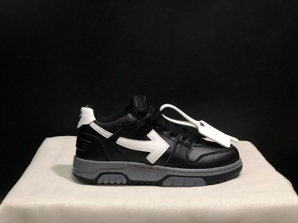 Side profile of a single black sneaker with a white arrow detail, contrasting heel accent, and white lace accessory.