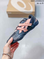 Side view of a black ASICS sneaker with pink layered side detailing, black laces, and a low-profile sole.