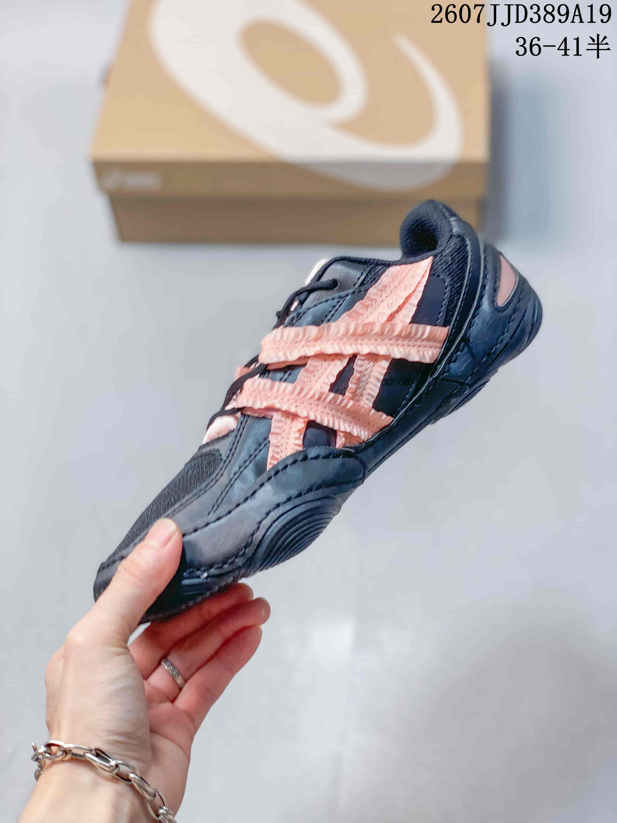Side view of a black ASICS sneaker with pink layered side detailing, black laces, and a low-profile sole.