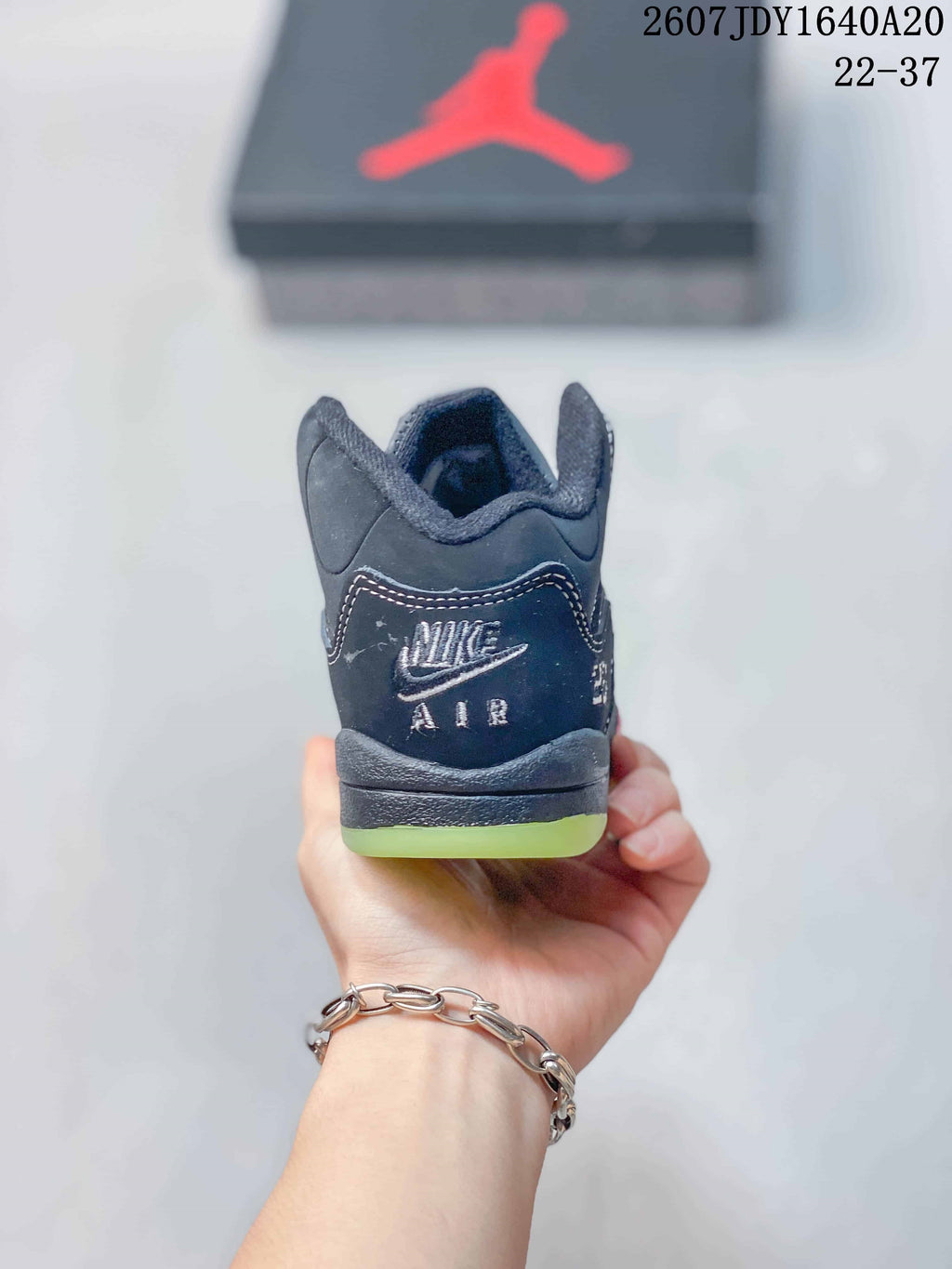 Rear view of the dark high-top sneaker showing the padded collar, heel branding, and lime-green outsole edge.