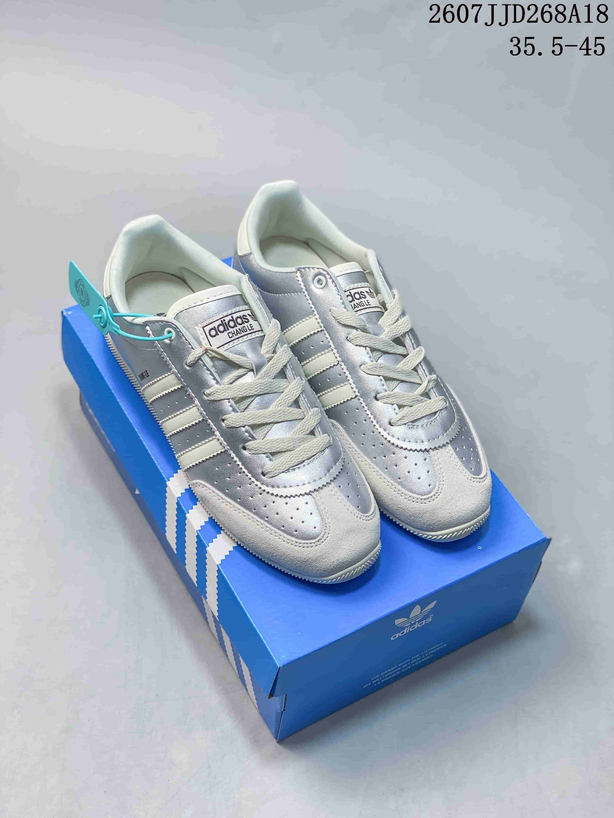 Pair of silver and white adidas Changle low-top sneakers displayed on a blue shoebox.