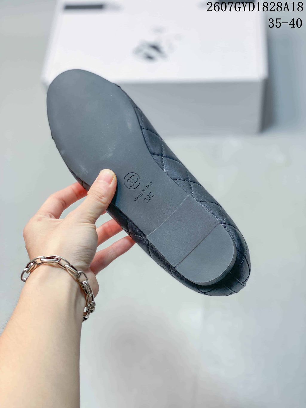 Black ballet flat shown from the outsole, with a circular logo and stamped markings visible.