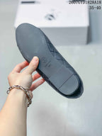 Black ballet flat shown from the outsole, with a circular logo and stamped markings visible.