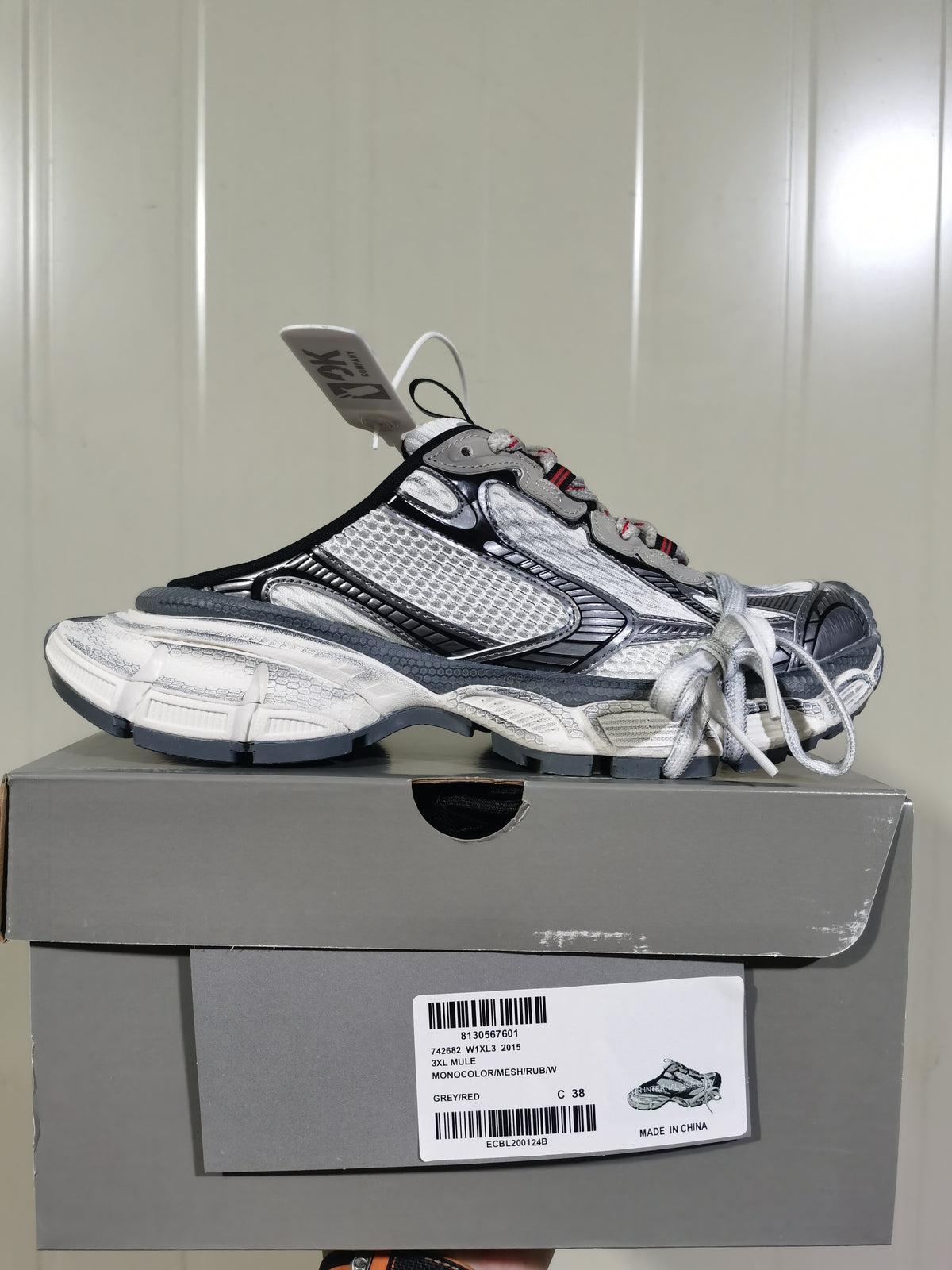 Side view of the sneaker resting on its box; the box label shows 3XL, model code 746282 W1XJ3 2015, Grey/Red and size C 38.
