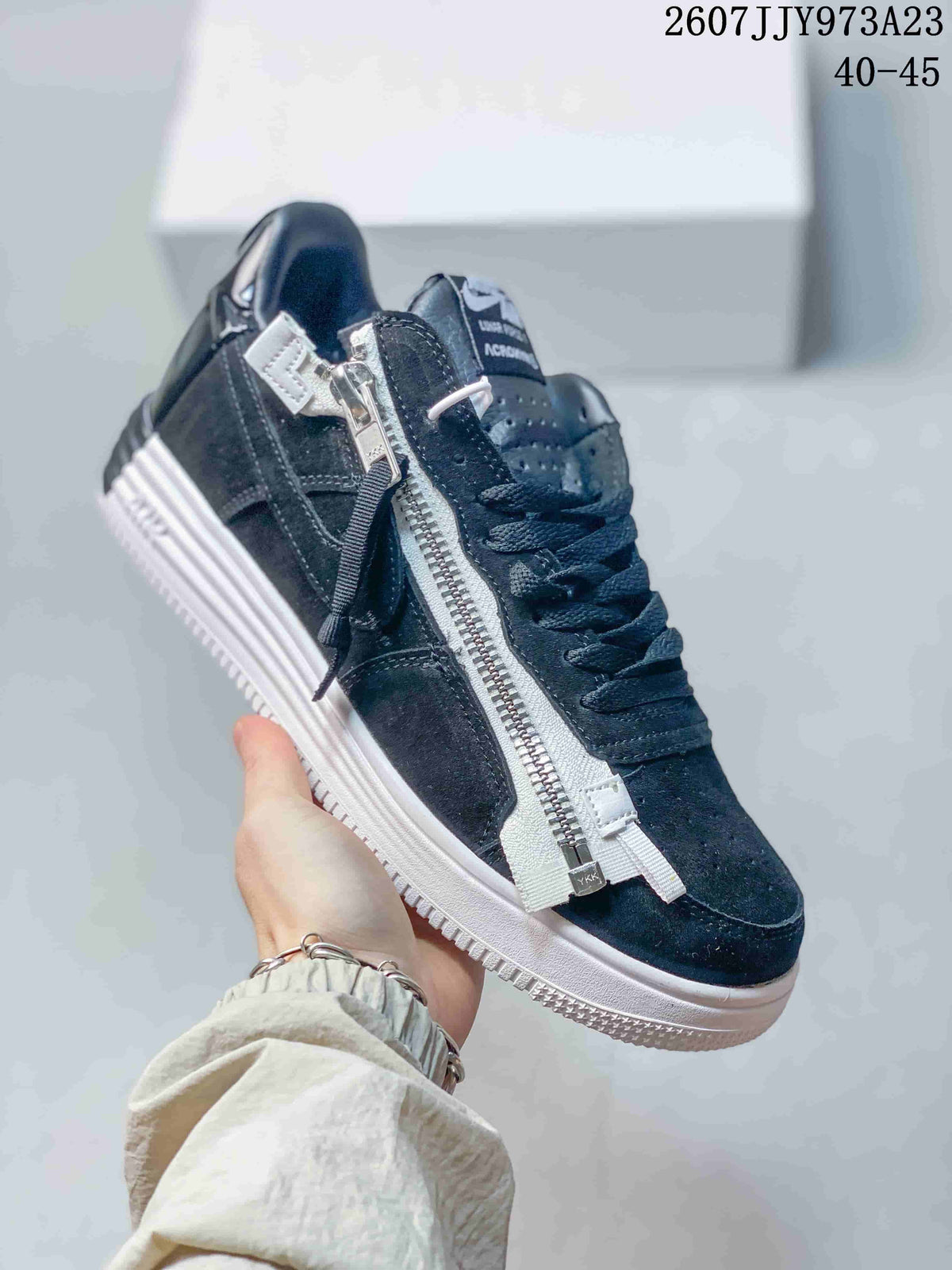 Angled side view of the black sneaker highlighting the full-length silver-tone zipper, strap accents, laces, and white outsole; image text shows product code 2607JJY973A23 and size range 40–45.